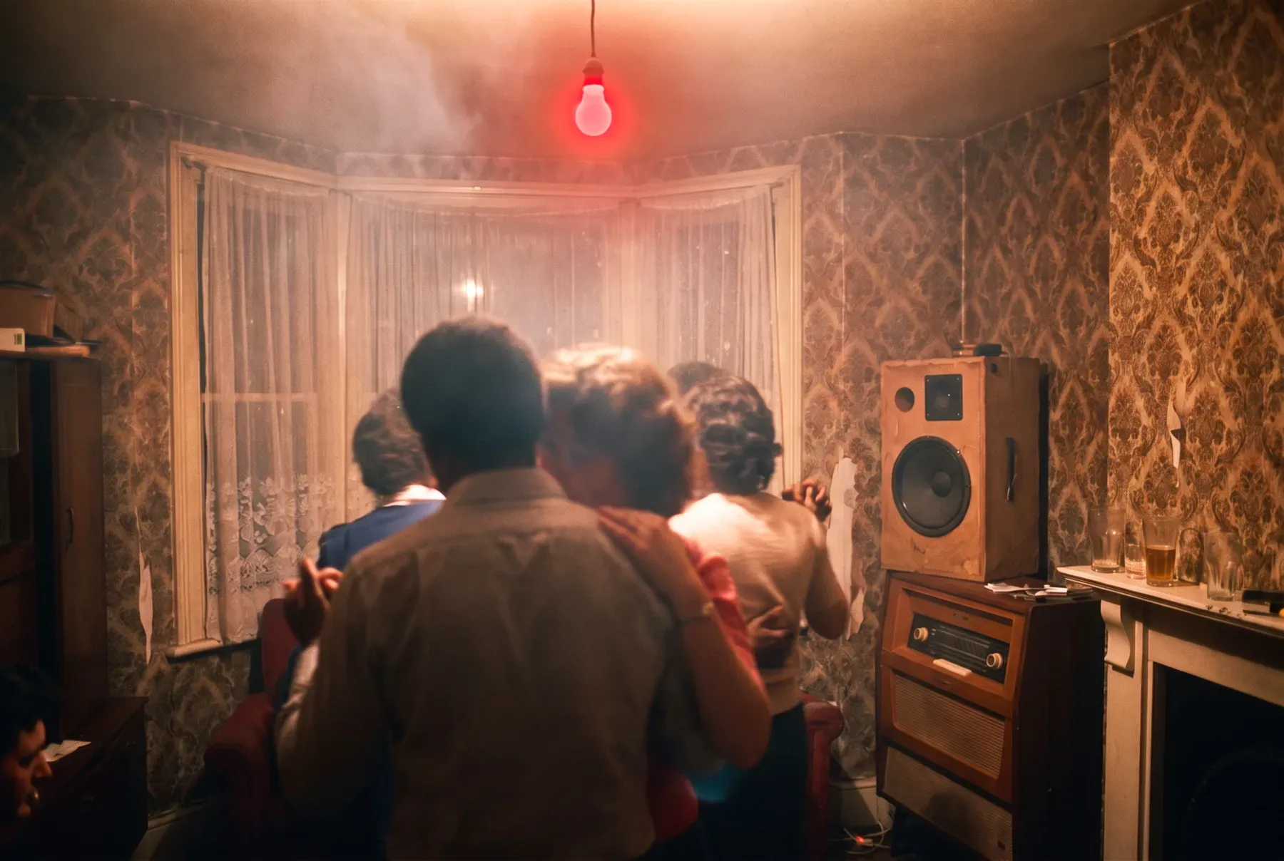 A blues party in a terraced front room under a red bulb, couples slow dancing beside a radiogram
